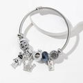 Zilveren kralenarmband met kroon- en beerbedeltjes en blauwe glazen kraal op standaard - Zwart