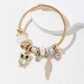 Bohemian gouden spiraalarmband met uil, veer en kristallen bedeltjes - Wit