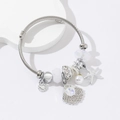 Silver stainless steel wire bracelet with starfish charms and white pearls on white stand - White