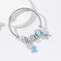 Detailed close-up of seaside charm bracelet with starfish, turtle, and pearl pendants - Blue