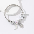 Silver beaded bangle with owl moon charms and handmade pendants on white display - White