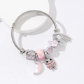 Silver owl and moon charm bracelet with pink crystals on a clean white display stand - Pink