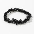 Detailed view of polished black irregular natural stone beads on an elastic bracelet - Black