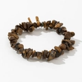 Macro shot of irregular tiger eye crystal stone elastic bracelet with silk luster texture - Brown