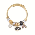 Goldenes Evil Eye Armband mit Kristallperlen und Spiralstruktur auf weißem Hintergrund - Schwarz