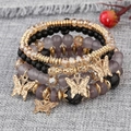 Détail d'un ensemble de 4 bracelets bohèmes avec perles et breloques papillon dorées - Gris Foncé