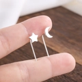 Macro shot of minimalist S925 silver star and moon stud earrings held by hand - Star Moon Style (239)