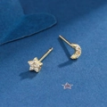 Asymmetric gold star and moon stud earrings with sparkling cubic zirconia on blue background - Gold