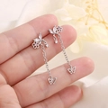 Pendientes de mariposa de plata con circonitas lila mostrados en la mano - Plata (A144)