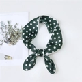 Dark green polka dot silk scarf tied in a bow on a white minimalist background - Green