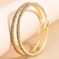 Dettaglio di orecchini a cerchio dorati da 6 cm con strass scintillanti in primo piano - Base Oro Viola