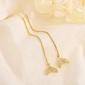 Elegantes pendientes largos de cola de pez dorados con circonitas sobre tela blanca suave - Dorado