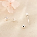 Boucles d'oreilles minimalistes en argent S925 en forme de cube sur un tissu texturé - Argenté