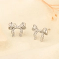 Detailed close-up of silver bow stud earrings with a textured metallic grain finish - White Gold (258)
