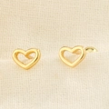 Eleganti orecchini a lobo a cuore cavo dorato con chiusura a vite su tessuto beige - Oro