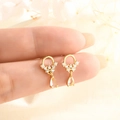 Elegante goldene Tropfenohrringe mit Zirkonia-Kristallen in den Fingern gehalten - Wasserblumen Tropfen Zirkonia Stil (A184)