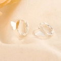 Elegant silver butterfly hoop earrings displayed on a textured beige fabric background - Silver Color (HL-107)