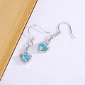 Elegantes pendientes de corazón plateados con piedras azul cielo sobre fondo de madera - Circonita Azul
