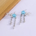 Boucles d'oreilles étoile argentées avec pierres bleues et franges sur fond bois - Or Blanc