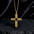 Dettaglio della collana vintage a croce d'oro con pietre nere su roccia scura - Stile X Oro Nero