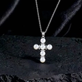 Dettaglio di un ciondolo a croce di perle con zirconi su uno sfondo di pietra nera ruvida - Stile F1 Argento Bianco