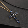 Golden cross necklace with blue teardrop cubic zirconia on black leather background - Blue Gemstone