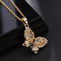 Détail du pendentif papillon doré orné de zircons colorés sur un support noir élégant - Papillon en diamant baguette coloré (J)
