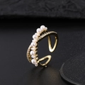 Macro shot of gold adjustable ring with pearls and pavé cubic zirconia on black background - Cross Starry Pearl Style (X)