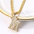 Gros plan du collier couronne dorée avec pendentif lettre M en zircons sur céramique - Lettre M
