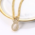 Vue macro du pendentif couronne lettre O dorée avec zircons sur une chaîne cubaine - Lettre O
