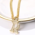Détail macro du pendentif couronne lettre R doré avec zircons sur une chaîne cubaine - Lettre R