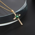 Vista macro di collana a croce dorata con pietra a cuore smeraldo e zirconi bianchi - Zirconia Verde Cuore Dorata (W)