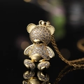 Primer plano del colgante de oso bañado en oro con circonitas sobre fondo negro - Estilo R (Oso Trepador 3D Brillante)