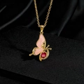 Collier papillon doré avec ailes roses et gemme rouge sur un support élégant noir - Papillon à ailes roses et pierre rouge sur fond doré (V)