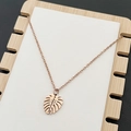 Collana con ciondolo a foglia di monstera oro rosa lucido su supporto in legno - Oro rosa