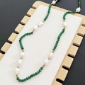 Baroque pearl necklace with green faceted beads and gold accents on a wooden display stand - Green Beaded Necklace