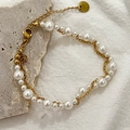 Elegantes Edelstahl-Perlenarmband mit verschiedenen Perlengrößen auf grauem Steingrund - Perlenarmband