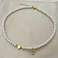 Elegante collar de perlas con colgante de corazón dorado y letra D brillante sobre seda rosa - Letra D