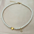 Collar de perlas hecho a mano con corazón dorado y colgante letra O sobre seda champán - Letra O