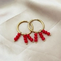 Elegant gold hoop earrings with red beaded tassels on premium textured silk fabric background - Red