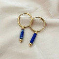 Gouden oorringen met blauwe stenen hangers op een lichtbeige zijden achtergrond - Blauw Marmer
