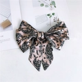 Detail of pink paisley satin ribbon bow with long tails on lifestyle magazine - Paisley Pink