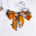 Detail of a bright orange satin skinny scarf with architectural patterns and a bow design - Warm Home Yellow