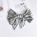 Detail of a blue and yellow striped satin bow hair clip placed on a fashion magazine - Striped Grey