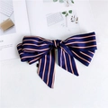 Close-up of navy blue satin striped bow scarf with ribbon tails on a white magazine - Striped Navy Blue