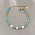 Handmade sky blue beaded bracelet with white pearls and gold accents on a grey surface - Bracelet / Lake Blue/Gold