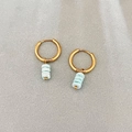 Golden round hoop earrings with light blue irregular stone bead pendants on grey fabric - Blue