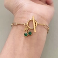 Dettaglio di un bracciale a catena a graffetta dorata con pendente a ciliegia verde - Verde