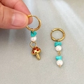 Asymmetrische gouden paddenstoel oorbellen met blauwe stenen en parels in de hand - Rode Paddenstoel Stijl