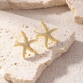 Close-up of elegant gold starfish stud earrings with sparkling zircon stones - Warm Gold Starfish Zirconia